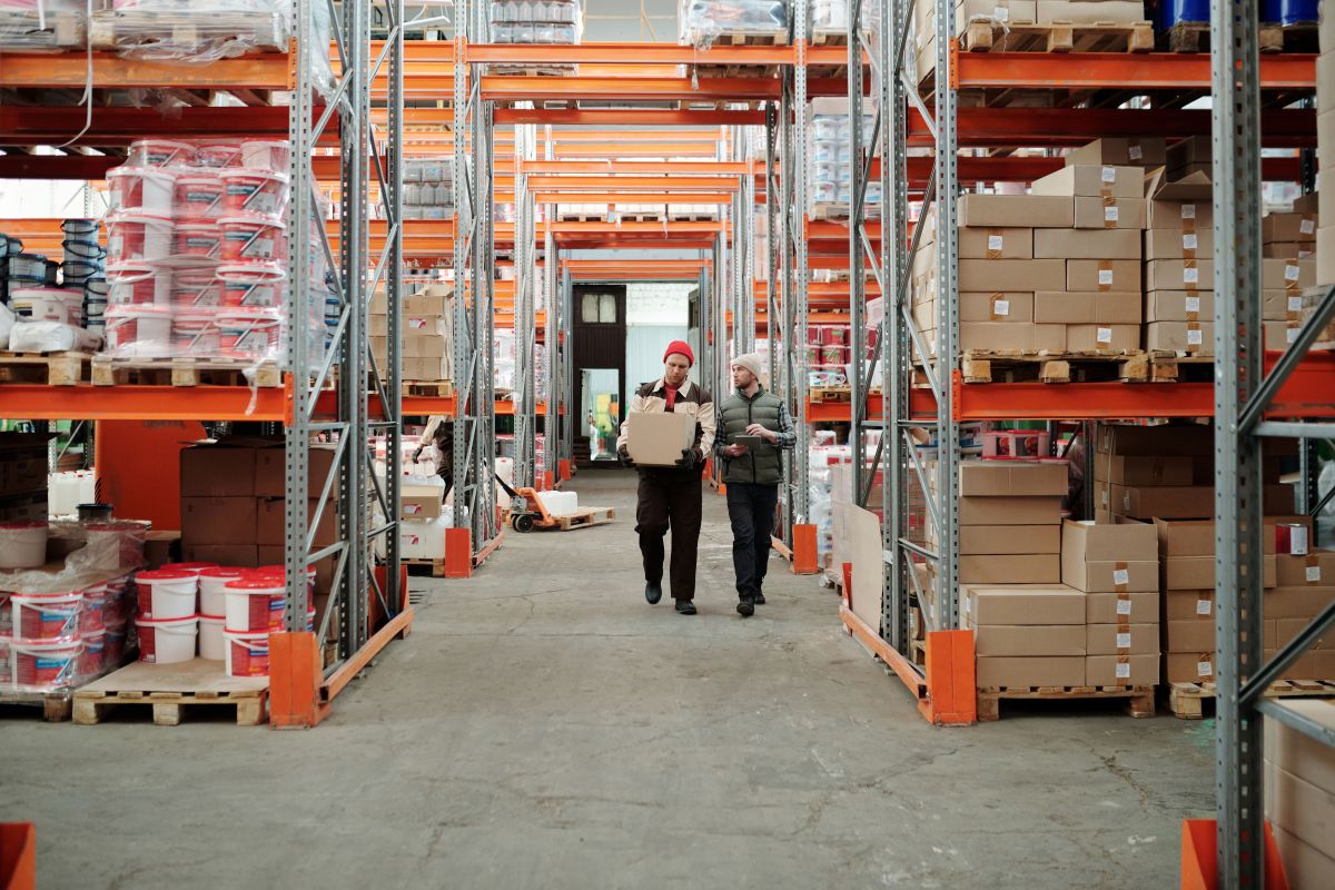 Inside a warehouse with stacked boxes and employees walking through